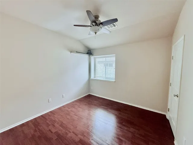 an empty room with wooden floor and ceiling fan
