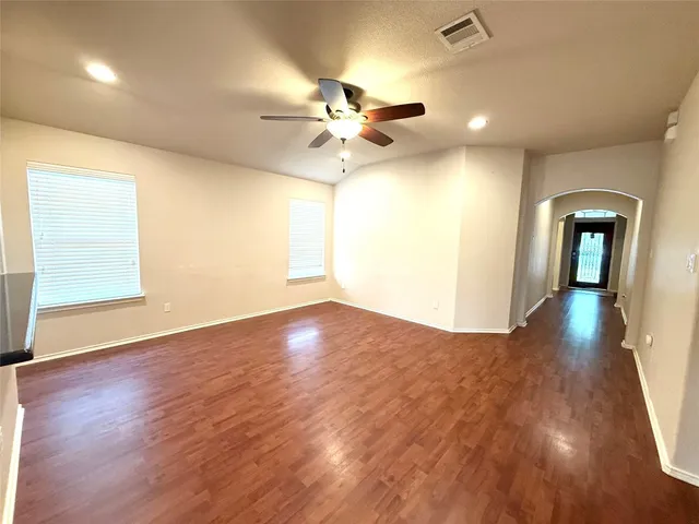 a view of an empty room with wooden floor and a window