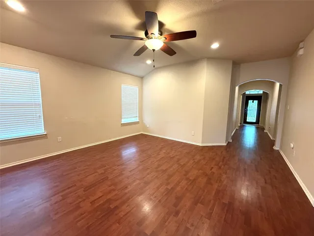 a view of an empty room with wooden floor and a window