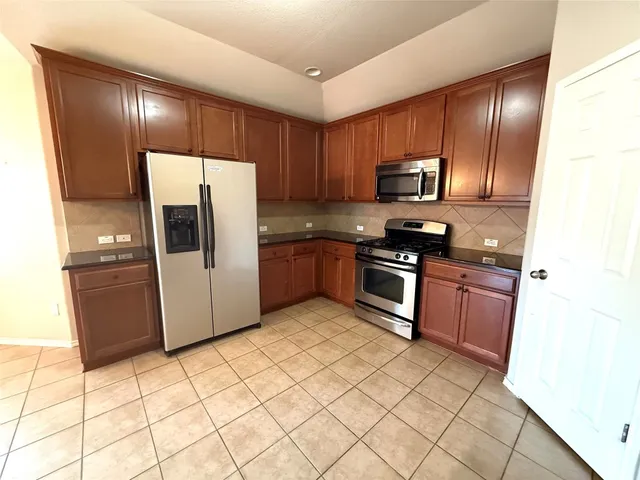 a kitchen with stainless steel appliances granite countertop a refrigerator stove top oven and sink