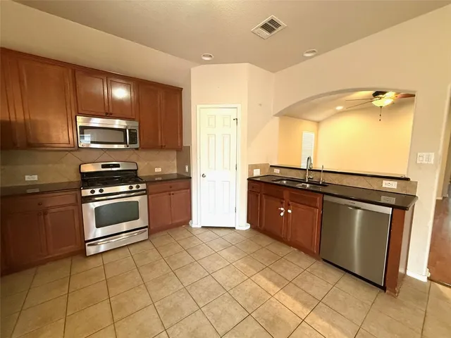 a kitchen with stainless steel appliances granite countertop a stove a sink and a microwave