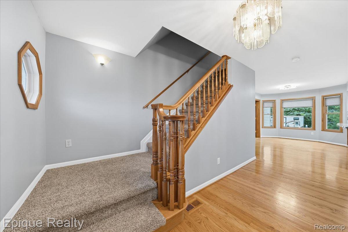 1221 Rhodes Road Lake Orion, MI 48360 - Photo 30 of 72 Staircase with wood balusters and handrail, featuring carpeted treads