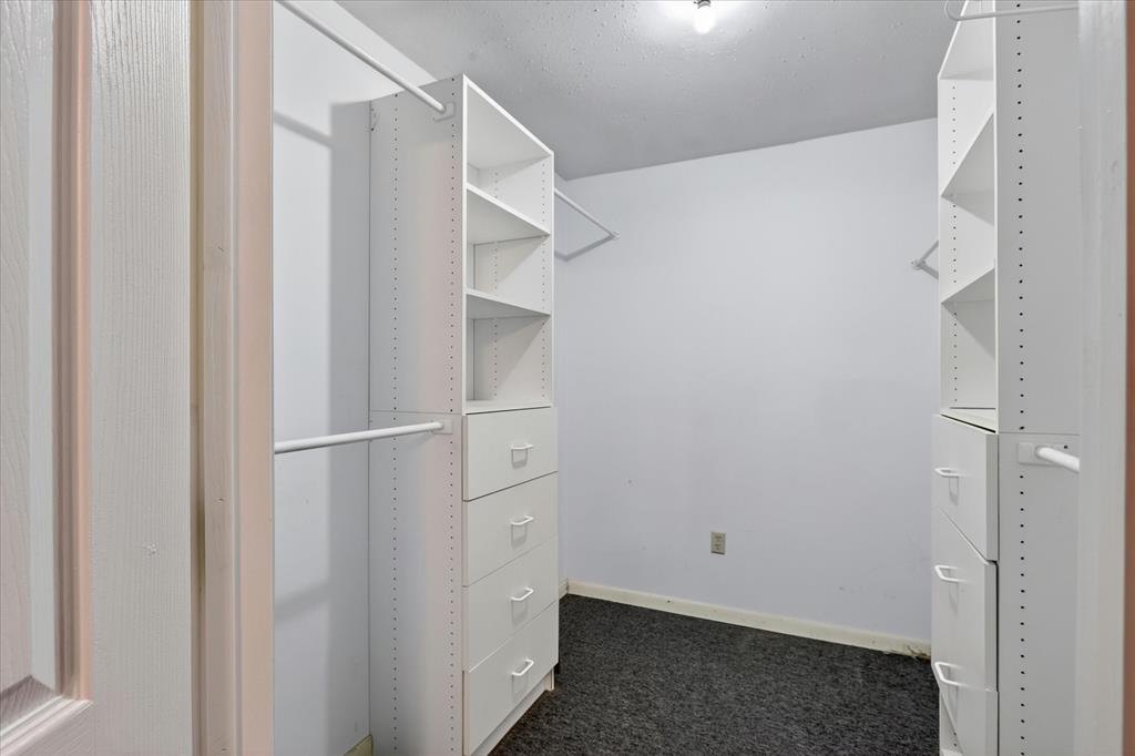 1092 West Highway 199 Springtown, TX 76082 - Photo 16 of 29 Walk-in closet featuring built-in shelving units, integrated drawers, white hanging rods, and dark carpet flooring