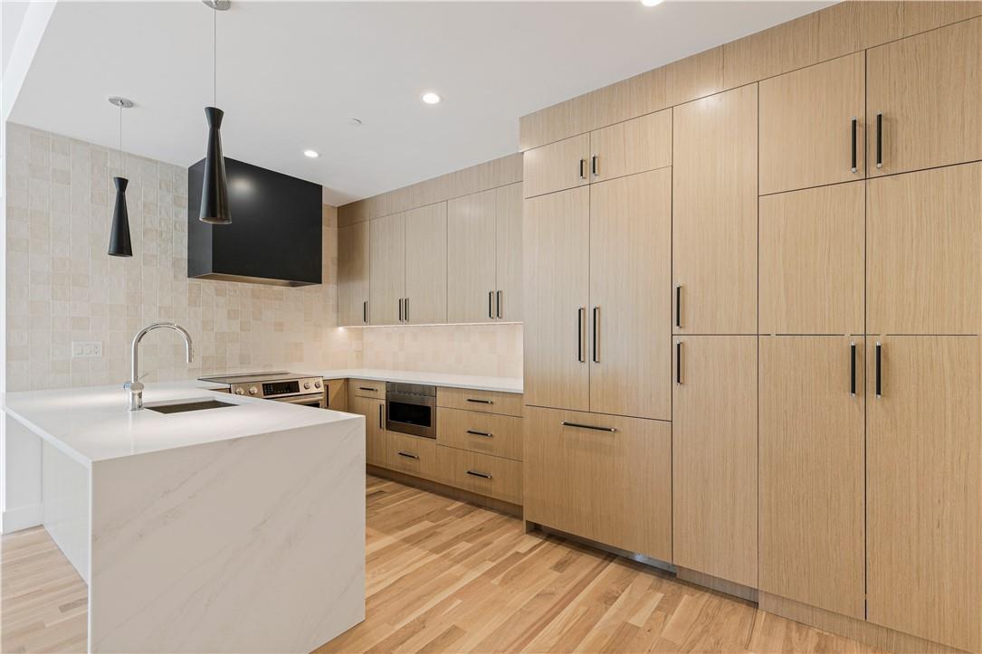 167 Purchase Street, Unit 21 Rye, NY 10580 - Photo 1 of 1 High end kitchen with light oak custom cabinets, waterfall counter, Bosch appliances, custom hood, and select designer lighting.
