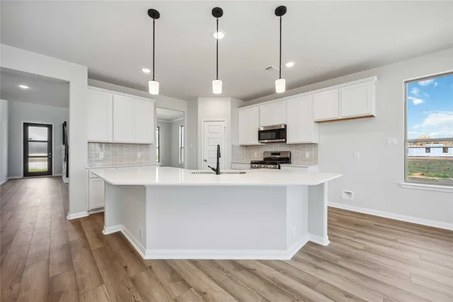 a kitchen with stainless steel appliances granite countertop a sink a stove a refrigerator and island with wooden floor