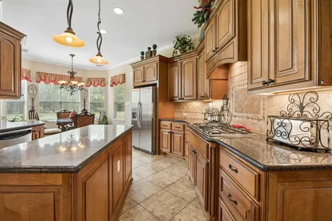 a kitchen with stainless steel appliances granite countertop a sink a stove and a wooden cabinets