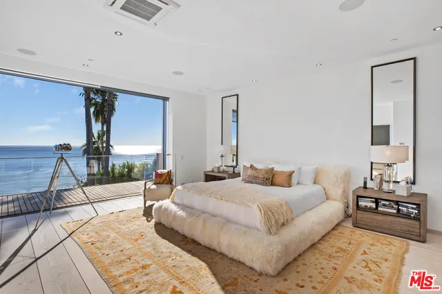 a vase of flowers sitting on a table with floor to ceiling window and wooden floor