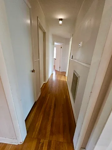 a view of a hallway with wooden floor and staircase