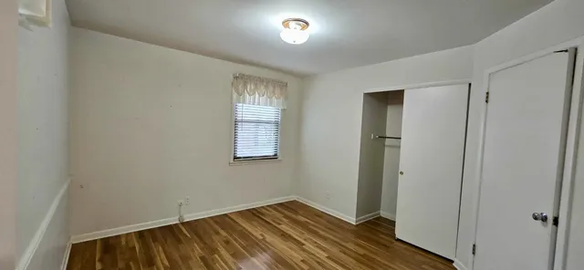 a view of an empty room with closet and a window