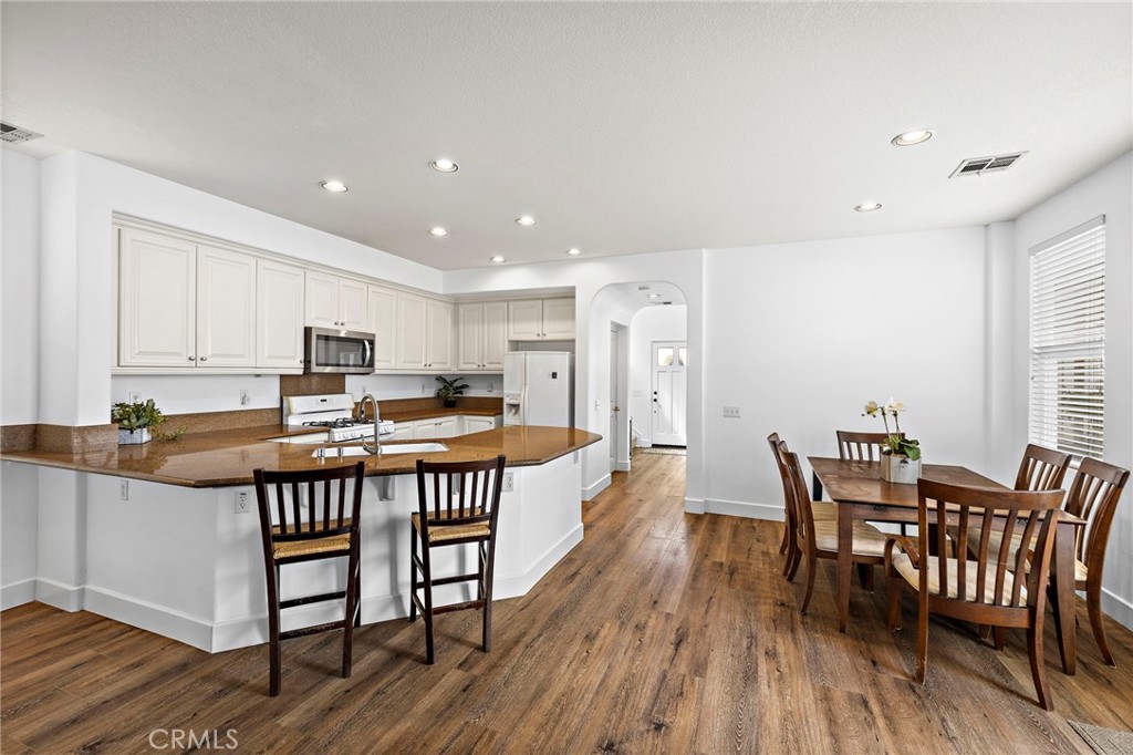 16 Skywood Street Ladera Ranch, CA 92694 - Photo 5 of 36 a kitchen with stainless steel appliances a dining table chairs and wooden floor