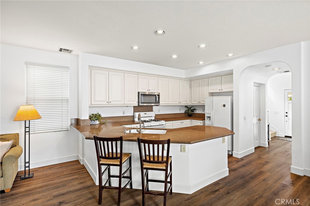 16 Skywood Street Ladera Ranch, CA 92694 - Photo 6 of 36 a kitchen with stainless steel appliances granite countertop table chairs sink and wooden floor