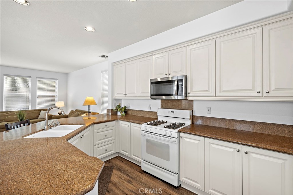 16 Skywood Street Ladera Ranch, CA 92694 - Photo 7 of 36 a kitchen with granite countertop a sink a stove cabinets and a window