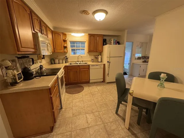 a room with a chair a stove a sink dishwasher and a refrigerator with wooden floor