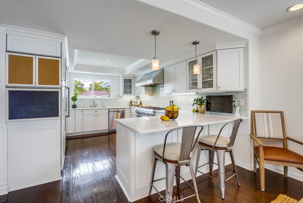 2879 Clubhouse Road Costa Mesa, CA 92626 - Photo 20 of 64 a kitchen with stainless steel appliances granite countertop a refrigerator a stove a sink dishwasher and white cabinets with wooden floor