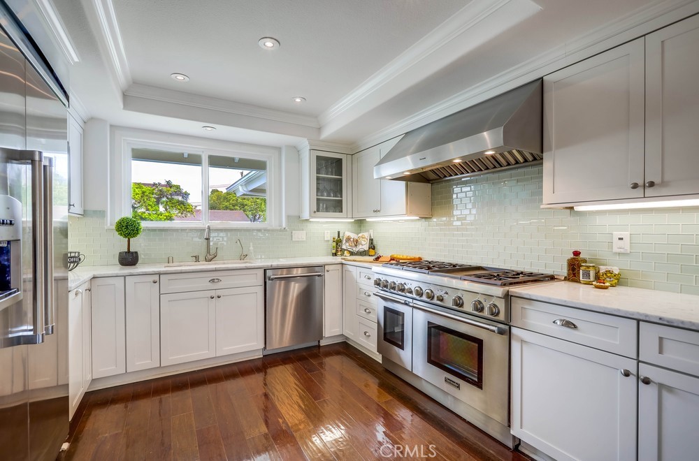 2879 Clubhouse Road Costa Mesa, CA 92626 - Photo 23 of 64 a kitchen with stainless steel appliances white cabinets and wooden floors