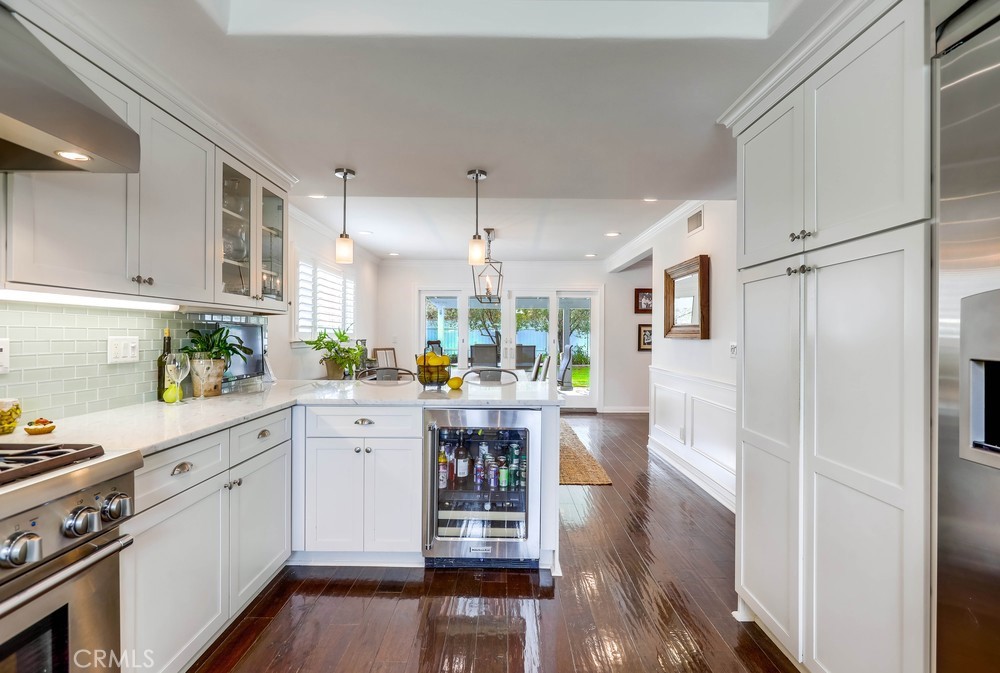 2879 Clubhouse Road Costa Mesa, CA 92626 - Photo 27 of 64 a kitchen with stainless steel appliances a white refrigerator a stove a sink dishwasher and white cabinets with wooden floor