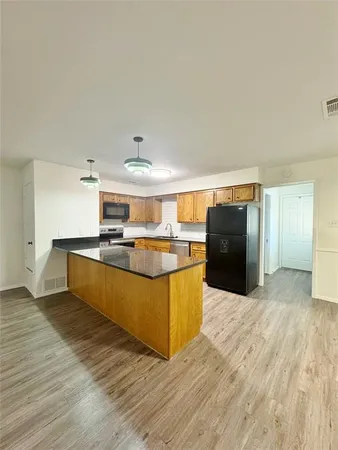 a kitchen with stainless steel appliances kitchen island granite countertop a large counter top and wooden floors