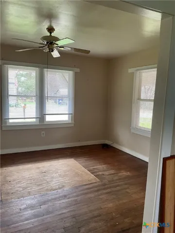 a view of an empty room with wooden floor and a window