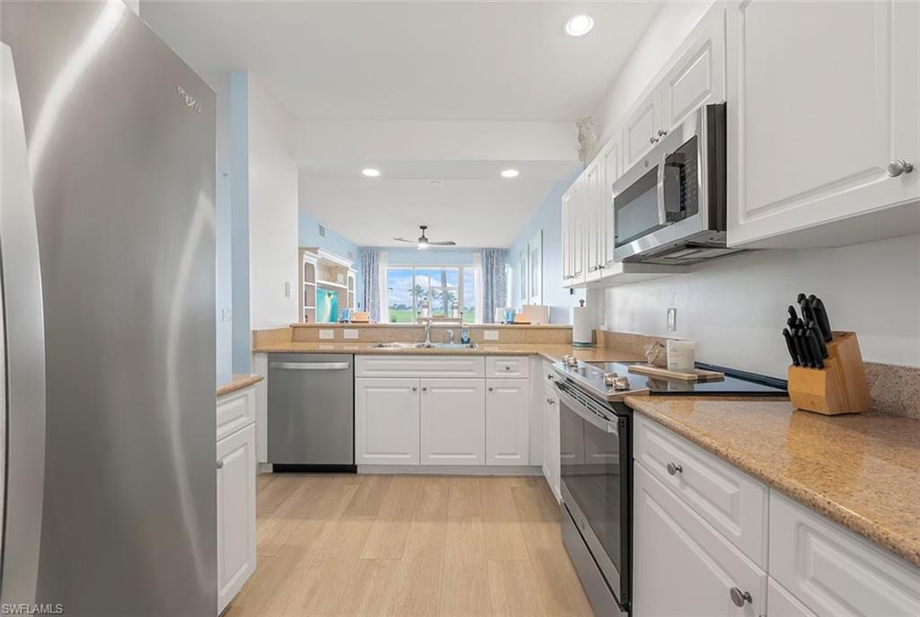 7915 Mahogany Run Lane, Unit 1114 Naples, FL 34113 - Photo 13 of 18 a kitchen with stainless steel appliances granite countertop a sink and dishwasher a stove top oven with wooden floor