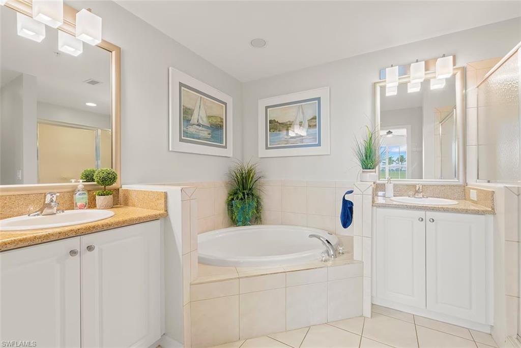 7915 Mahogany Run Lane, Unit 1114 Naples, FL 34113 - Photo 14 of 18 a bathroom with a granite countertop sink a mirror a vanity and a bathtub