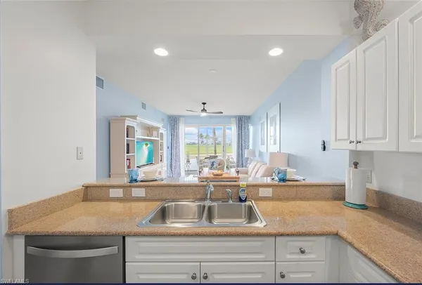 a kitchen with granite countertop a sink and white cabinets