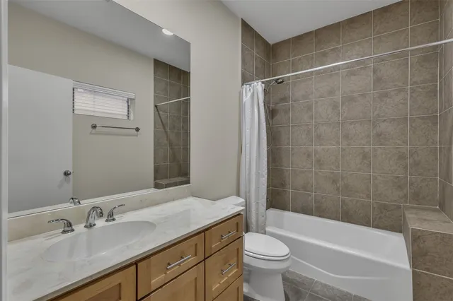 a bathroom with a bathtub shower sink mirror vanity and toilet