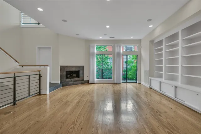 a view of an empty room with a window and wooden floor