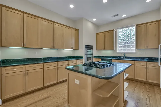 a kitchen with stainless steel appliances granite countertop a sink a stove and a refrigerator