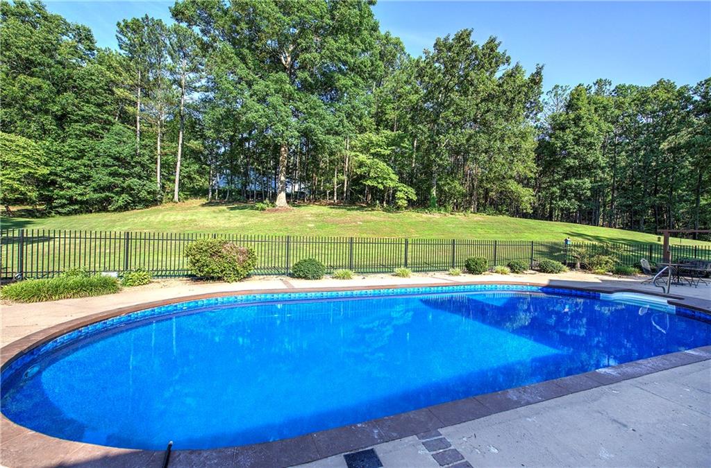 408 Mac Johnson Road Northwest Cartersville, GA 30121 - Photo 66 of 79 a view of a swimming pool with a yard and trees in the background