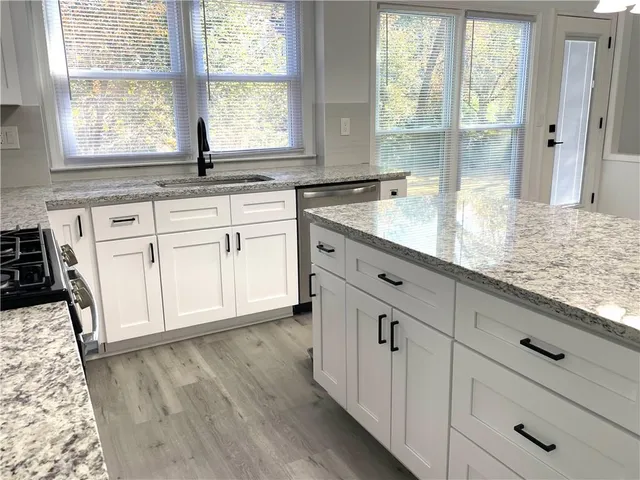a kitchen with granite countertop white cabinets and a large window