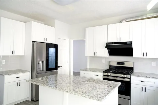 a kitchen with stainless steel appliances granite countertop a stove a sink and a refrigerator