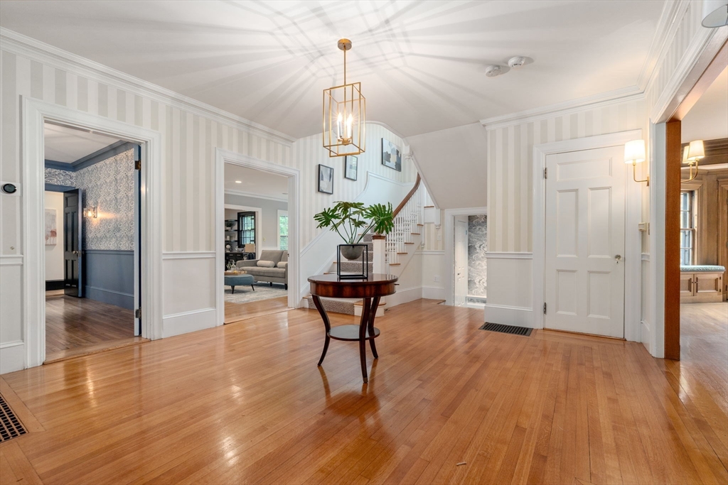 388 Warren Street Brookline, MA 02445 - Photo 3 of 34 a dining room with wooden floor a chandelier a wooden table and chairs