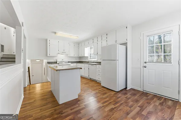 a kitchen with wooden floors white cabinets and stainless steel appliances