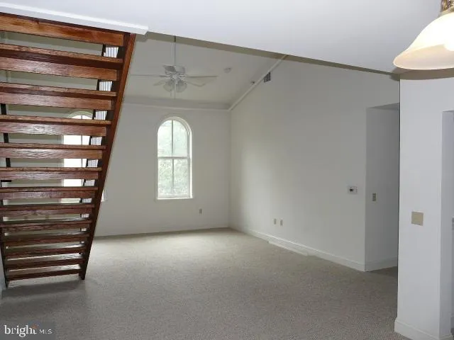 a view of empty room with stairs and wooden floor