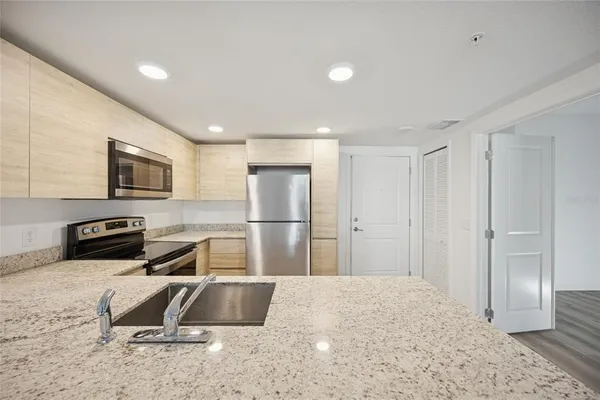 a kitchen with a refrigerator a stove and a sink with wooden floor