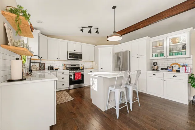 a kitchen with stainless steel appliances granite countertop a stove a sink a refrigerator a microwave oven with cabinets and wooden floor