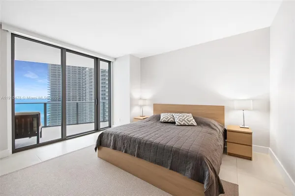 a bedroom with a bed and large windows