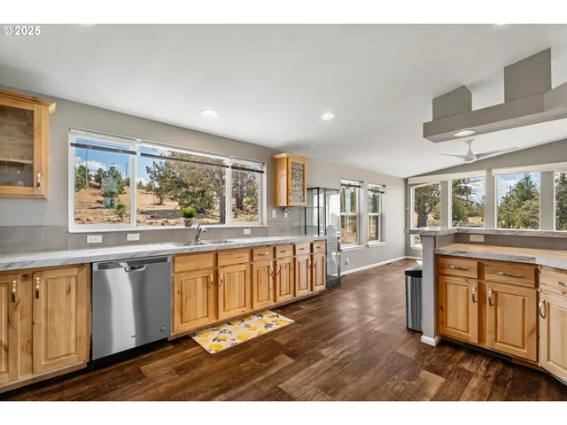 a open kitchen with stainless steel appliances granite countertop a stove top oven a sink dishwasher and cabinets with wooden floor