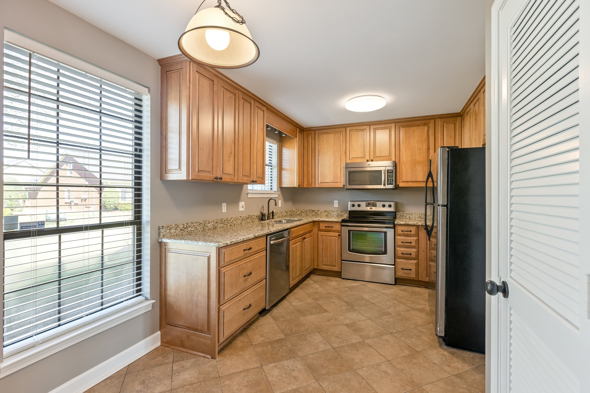 1216 General George Patton Road Nashville, TN 37221 - Photo 11 of 32 a kitchen with granite countertop stainless steel appliances a stove top oven a refrigerator a sink and dishwasher with large window
