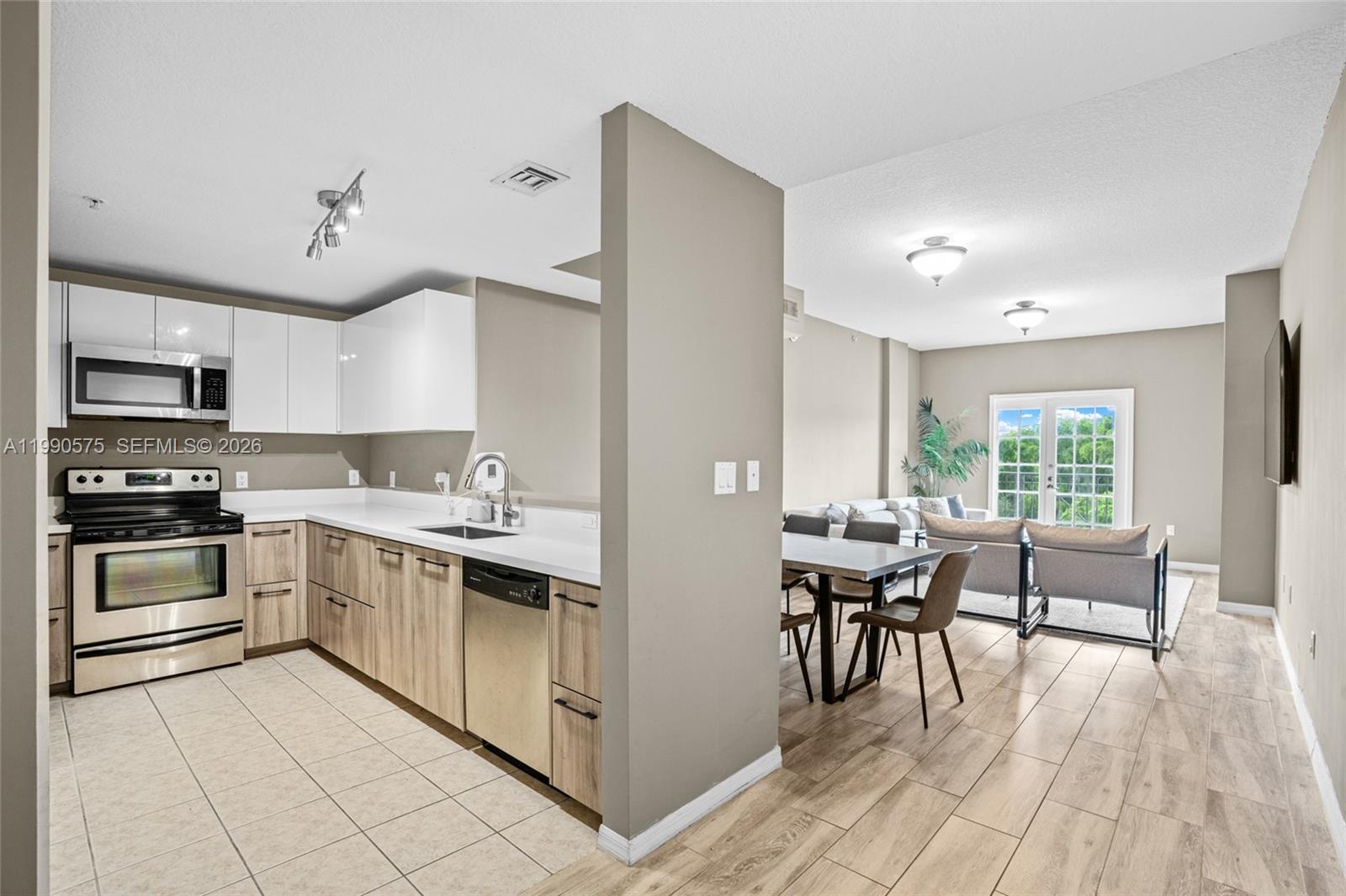 5271 Southwest 8th Street, Unit 315 Miami, FL 33134 - Photo 4 of 25 a kitchen with stainless steel appliances granite countertop a stove top oven a sink dishwasher and white cabinets with wooden floor