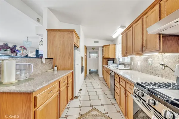 a kitchen with stainless steel appliances granite countertop a stove a sink dishwasher and a refrigerator