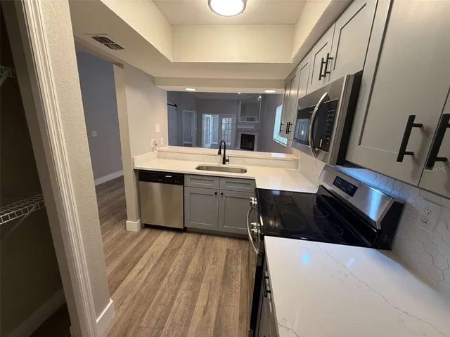 a view of a hallway with wooden floor and a bathroom
