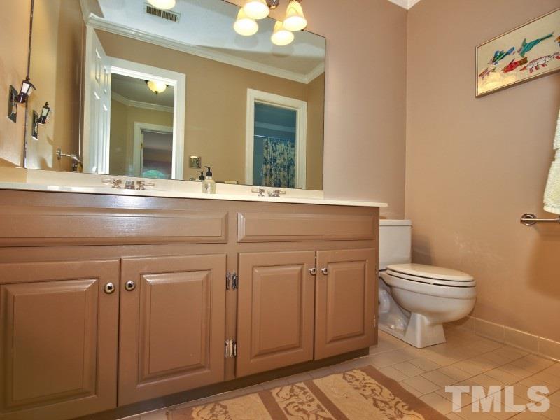 8917 Wildwood Links Raleigh, NC 27613 - Photo 22 of 25 a bathroom with a toilet a sink and a mirror