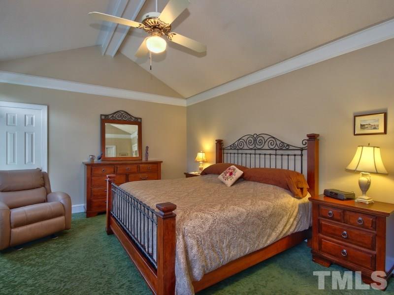8917 Wildwood Links Raleigh, NC 27613 - Photo 6 of 25 a bedroom with a bed a chandelier and a dresser