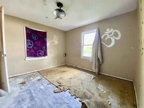 an empty room with wooden floor cabinet and windows