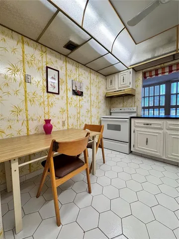 a kitchen with granite countertop cabinets a stove a dining table and chairs