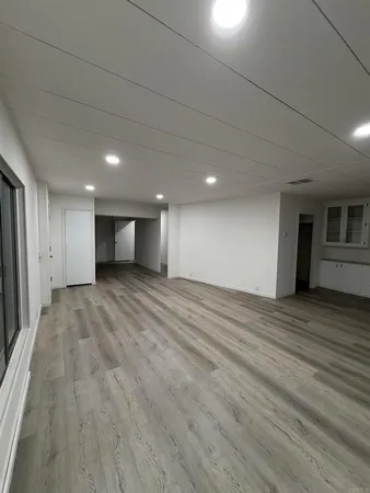 a view of an empty room with wooden floor and closet