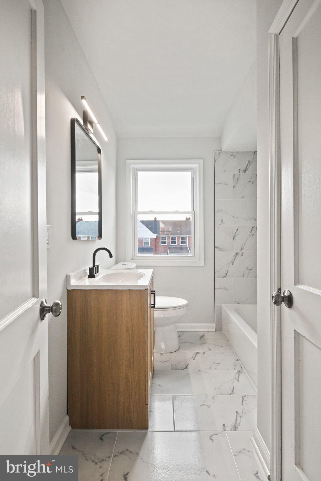 1322 Kitmore Road Baltimore, MD 21239 - Photo 15 of 34 a spacious bathroom with a toilet sink and mirror