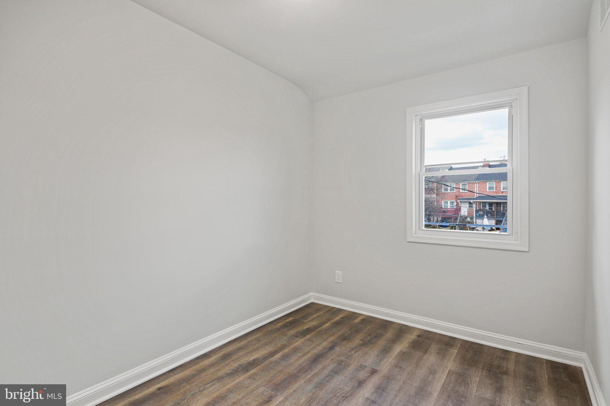 1322 Kitmore Road Baltimore, MD 21239 - Photo 21 of 34 a view of an empty room with wooden floor and a window