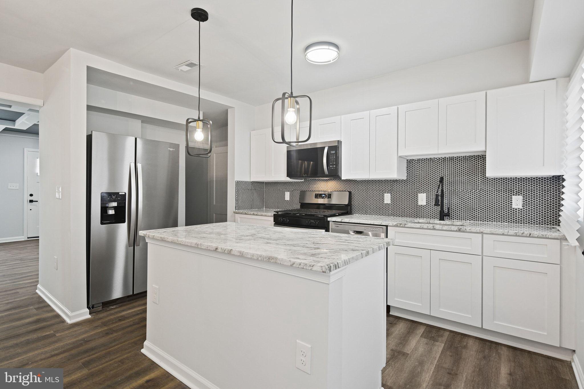 1322 Kitmore Road Baltimore, MD 21239 - Photo 8 of 34 a kitchen with stainless steel appliances granite countertop a sink a stove a refrigerator a center island with wooden floor and cabinets